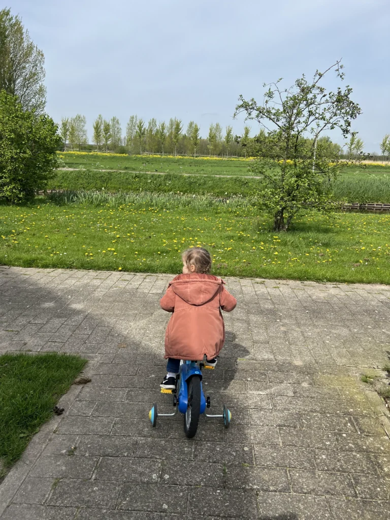 Peuter fietst naar grasveld met lentebloemen