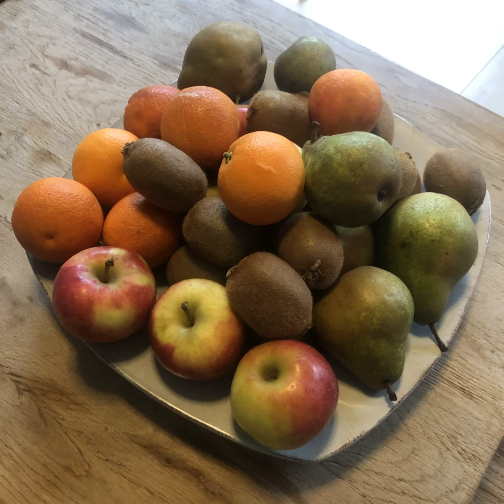 Volle fruitschaal met biologische appels, kiwi's, peren en mandarijnen zonder verpakking